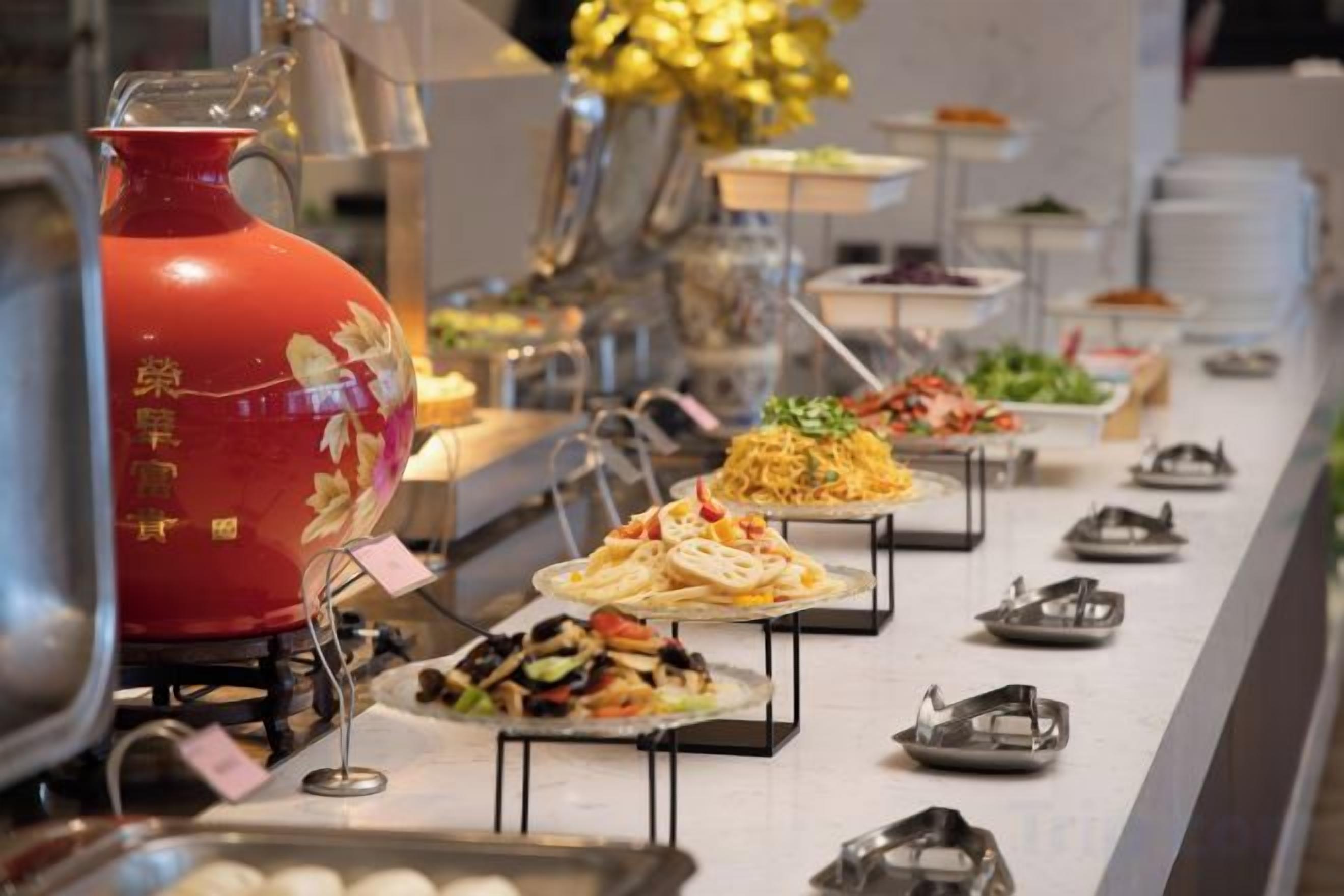 En buffet med forskellige retter og en rød dekorativ vase.