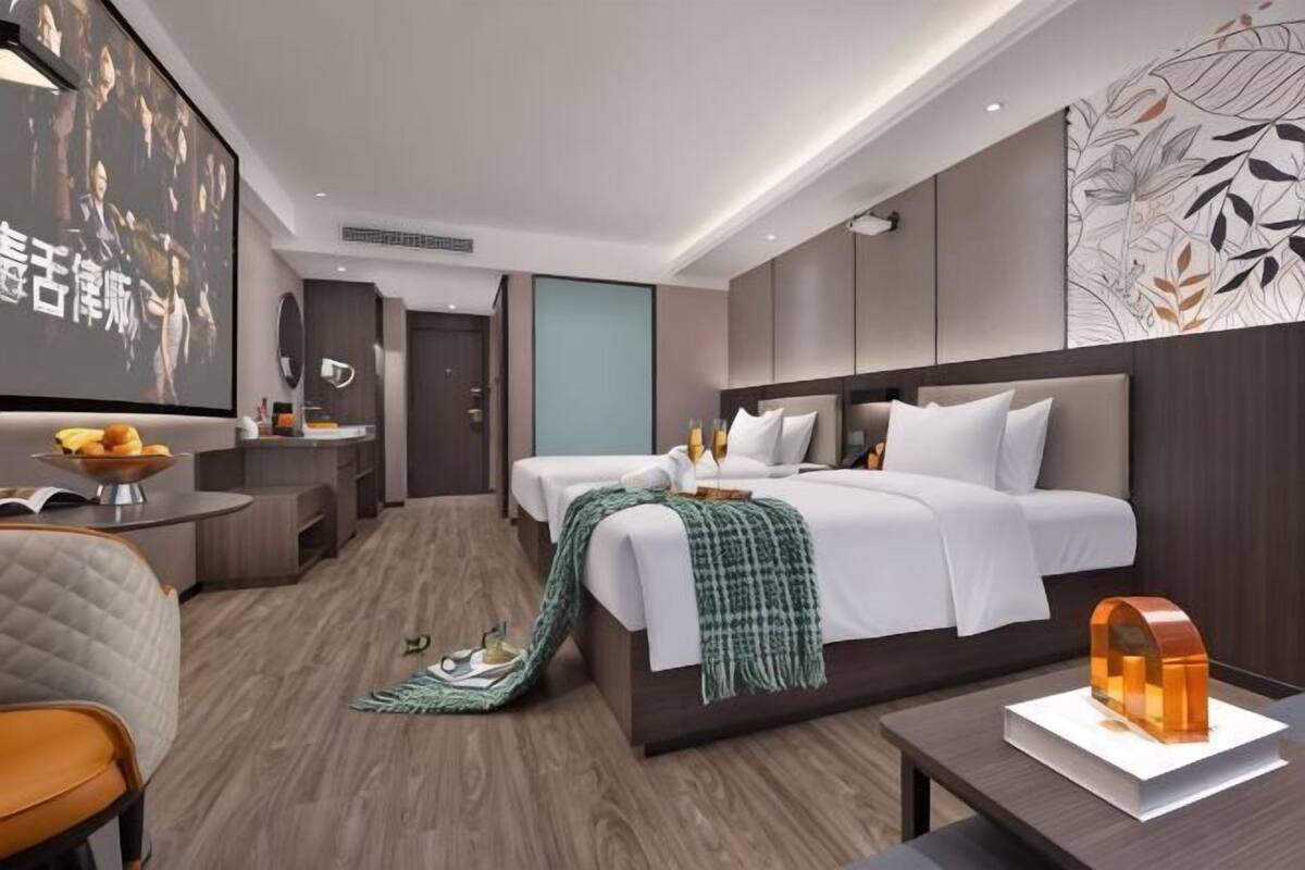 A modern hotel room with a large bed, a desk, a chair, and a television.
