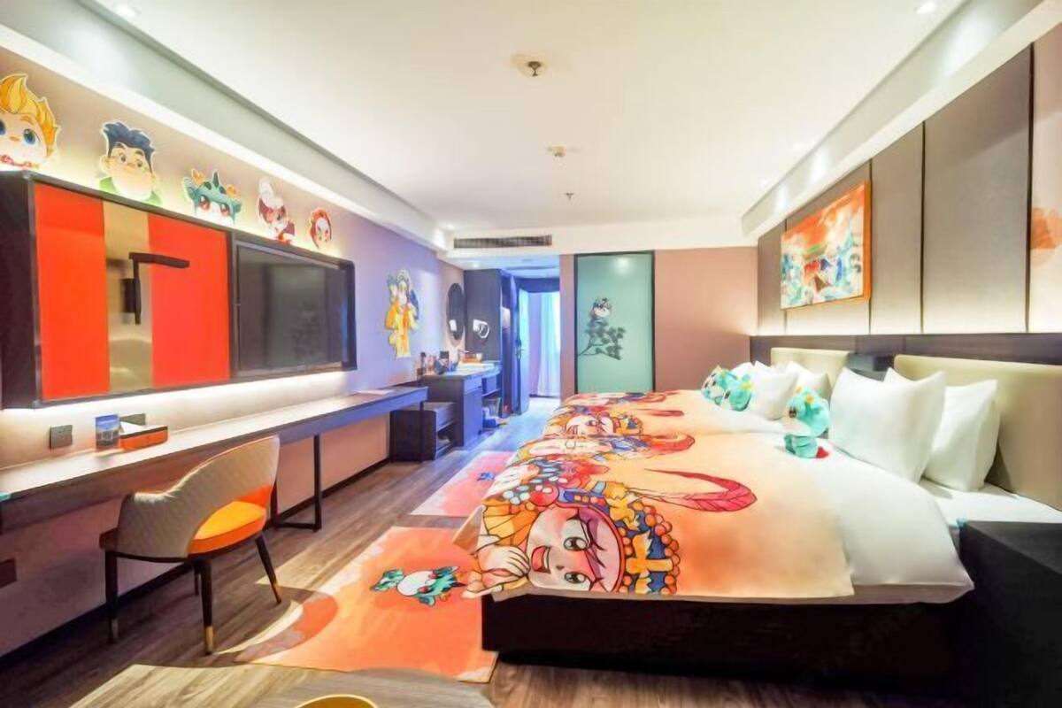 A hotel room with a bed, a desk, a chair, and a large mirror.