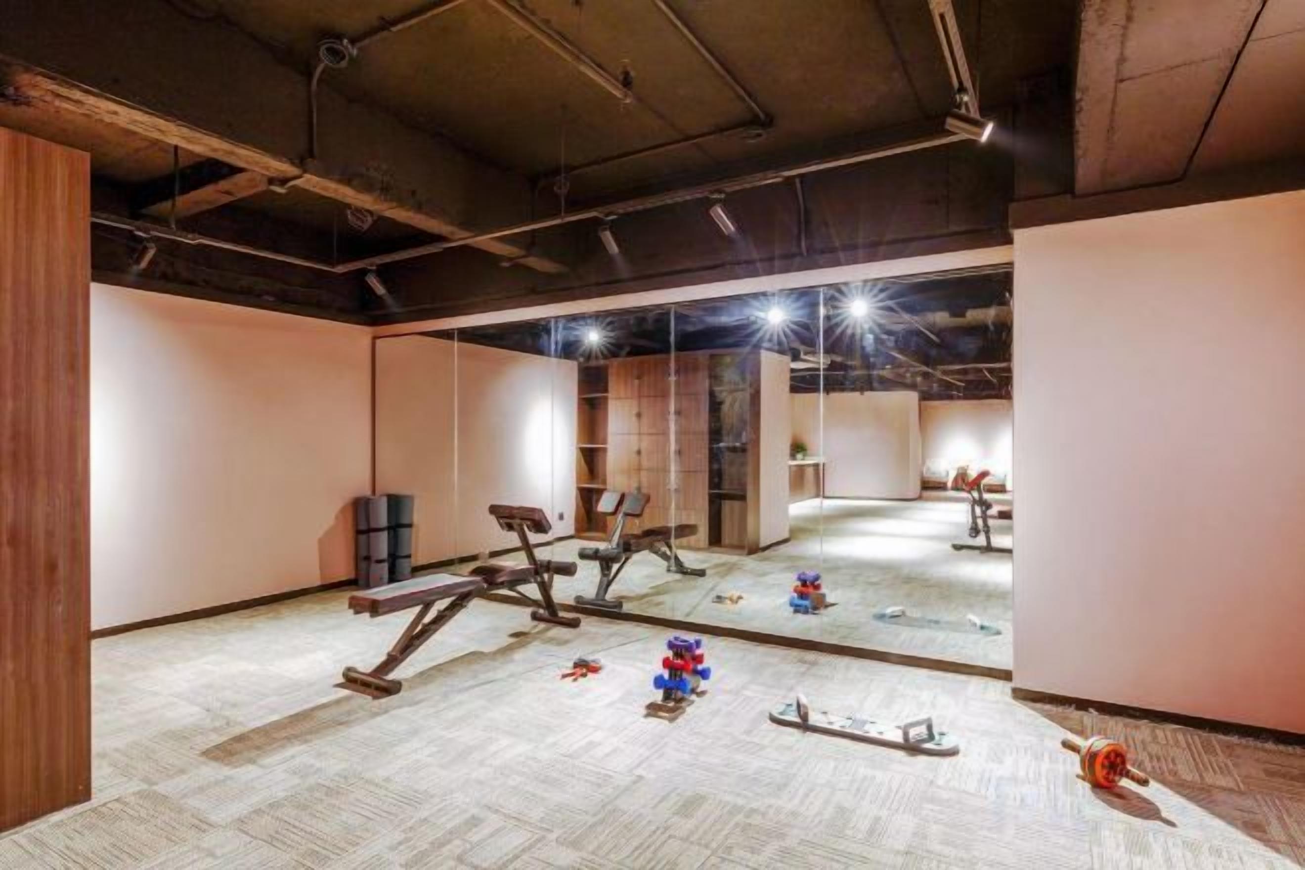 A gym with exercise equipment, a mirrored wall, and a carpeted floor.
