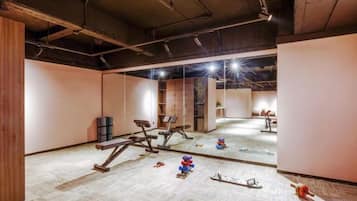 A gym with exercise equipment, a mirrored wall, and a carpeted floor.