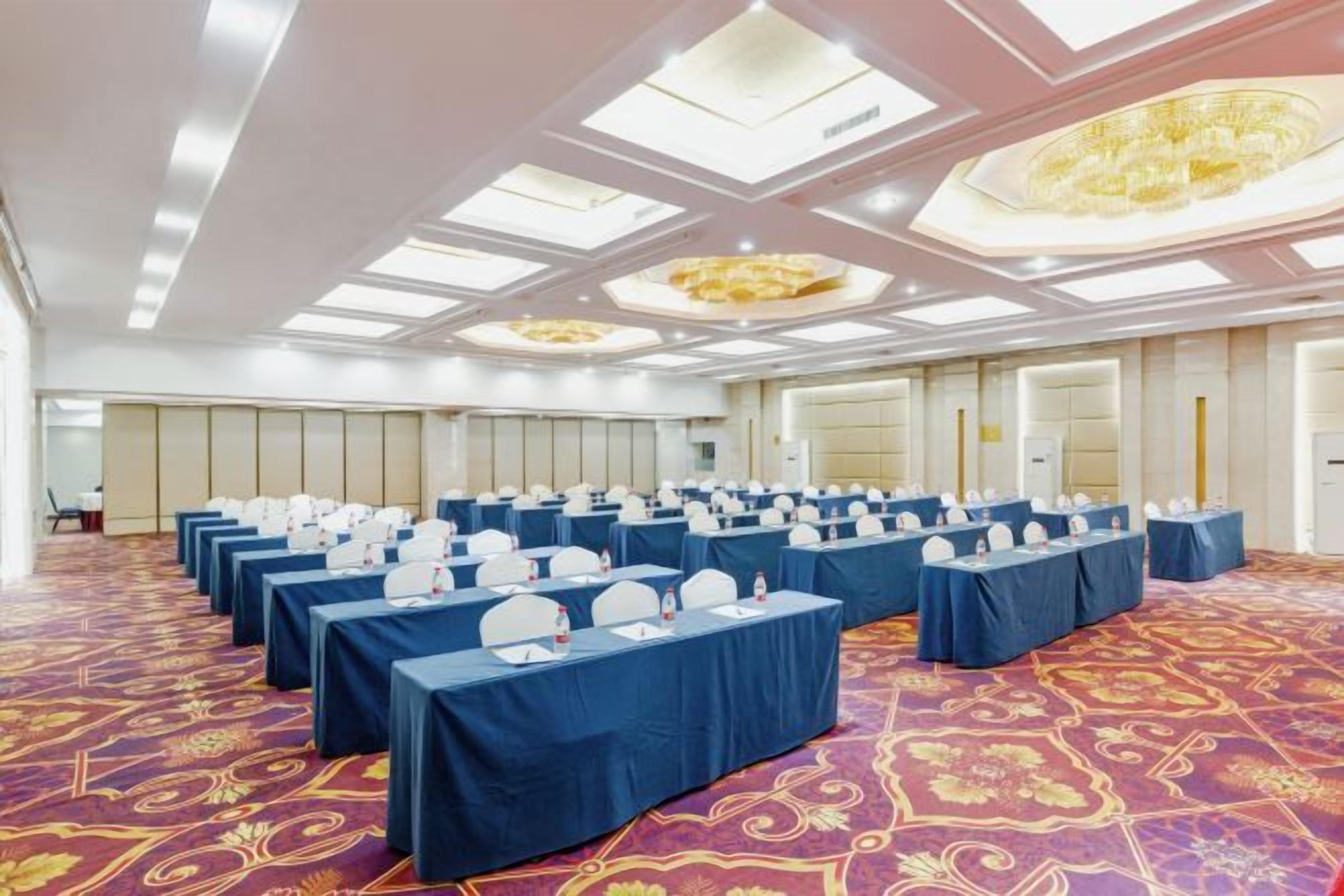 A conference room with rows of tables, chairs, and a carpeted floor.