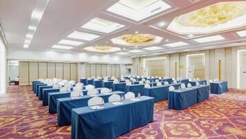 A conference room with rows of tables, chairs, and a carpeted floor.
