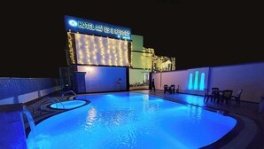 Un hotel con zona de piscina, un cartel que dice "HOTEL AAYES & RESORT" y un edificio decorado con luces de adorno.