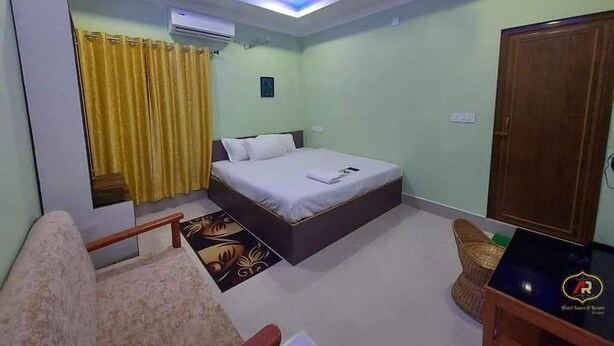 Un dormitorio con cama, ventilador de techo, aire acondicionado, armario de madera y una mesita con un logotipo.