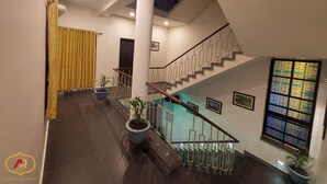 A modern hotel lobby with a staircase, potted plants, and framed pictures on the walls. - Hotel Aayes & Resort (Bolpur)