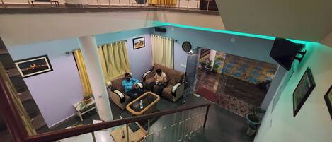 A multi-level living area with a sofa set, a dining table, and a staircase.