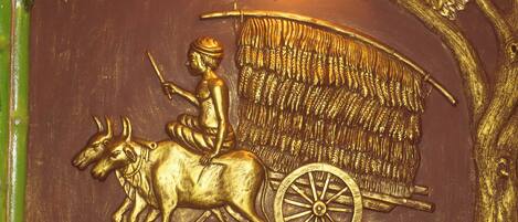 A detailed relief sculpture of a man on a horse-drawn cart, surrounded by foliage and birds.