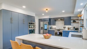 Una cucina moderna con mobili grigi, un'isola centrale con sedute e elettrodomestici in acciaio inossidabile.