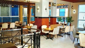 A restaurant with booths and tables, wooden beams on the ceiling, and large windows. - Blue top motel mbarara (Mbarara)