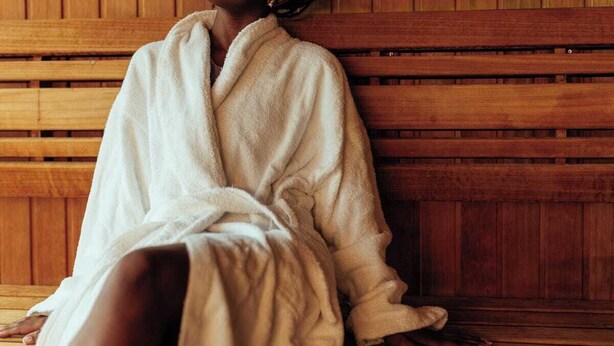 A person sitting on a wooden bench in a room with wooden paneling. - Blue top motel mbarara (Mbarara)