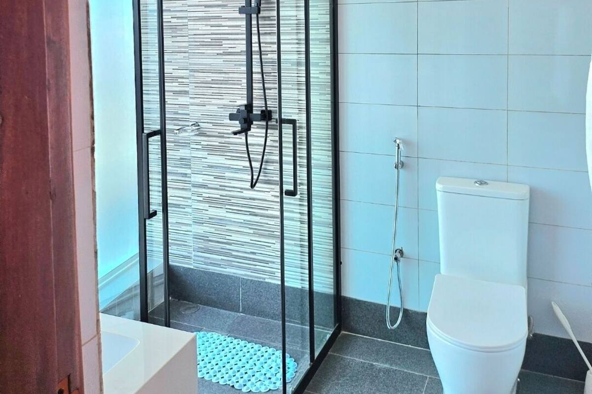 A modern bathroom with a glass-enclosed shower, a toilet, and a wall-mounted sink.