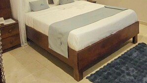 A bedroom with a canopy bed, a nightstand, and a blue rug. - Blue top motel mbarara (Mbarara)