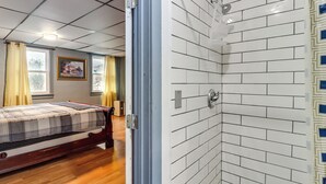 Una camera da letto con un letto, una doccia e una finestra con tende.