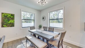 A dining room with a dark wooden table, cushioned benches, and a large window with a view of trees. - Stone's Throw to All Major Attractions: Family Gem (North Port)