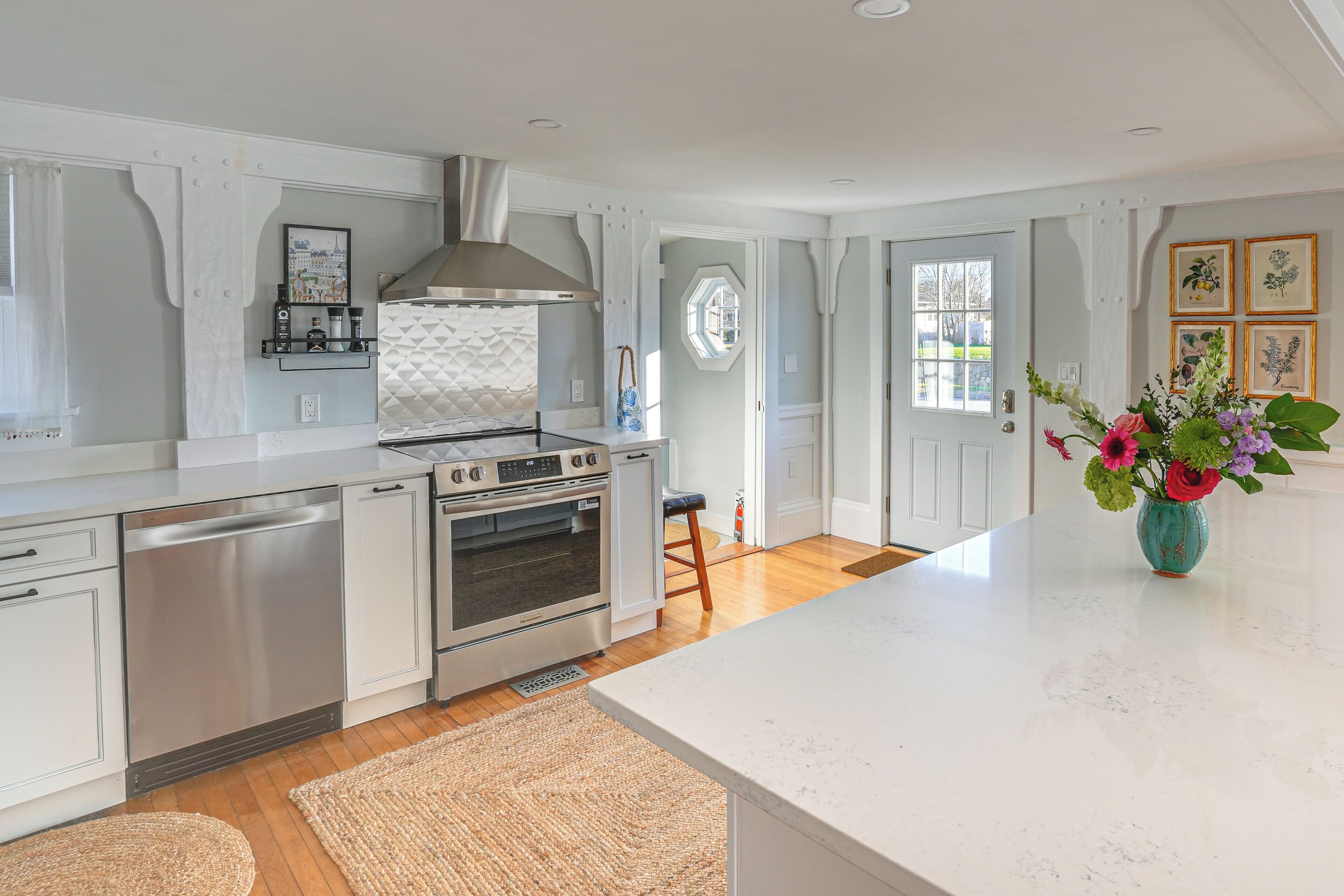 A modern kitchen with white cabinetry, stainless steel appliances, and a large island.
