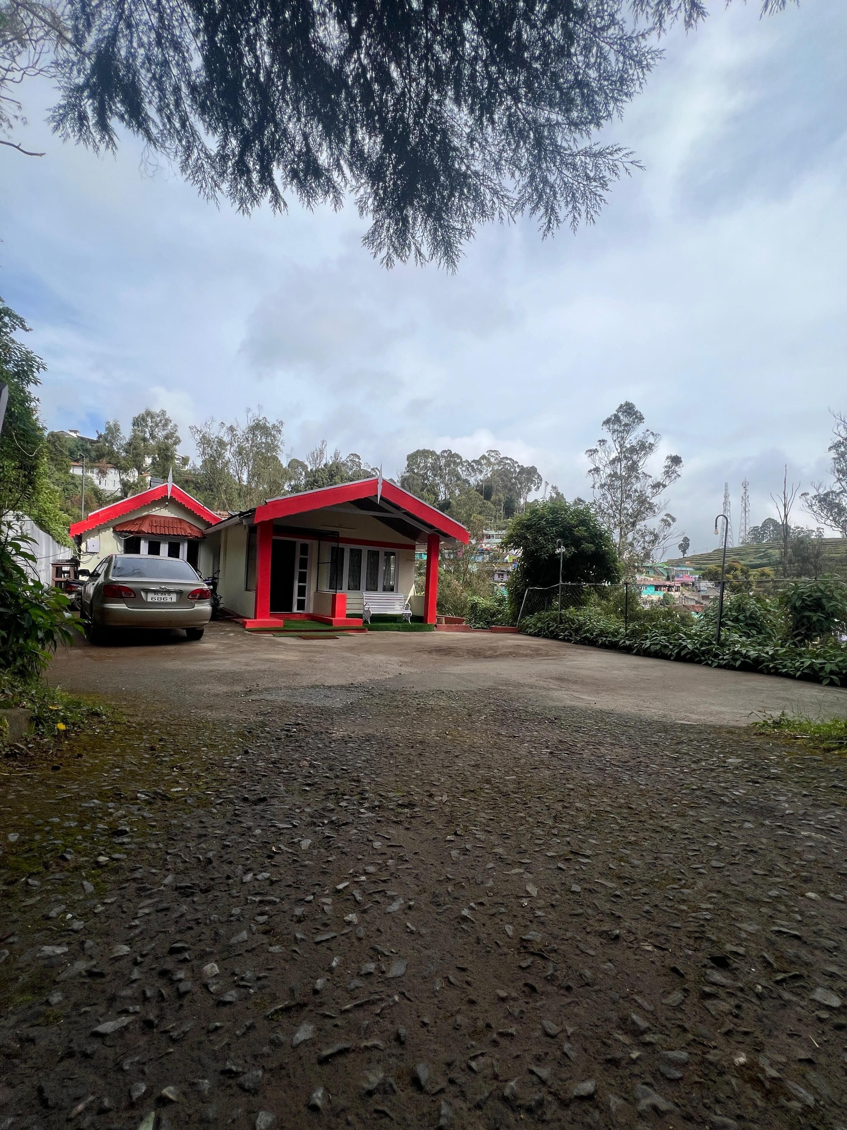 A house with a red roof, a driveway, and a car parked in front.