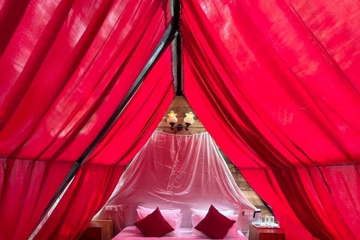 A bed with red curtains, a canopy, and a wooden headboard.