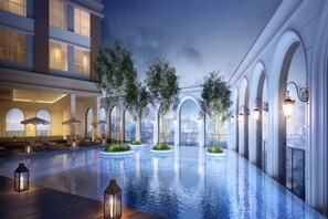 A modern hotel with a large indoor swimming pool, lounge areas, and arched windows. - Kotrip Luxstay River Gate Residence (Ho Chi Minh City)