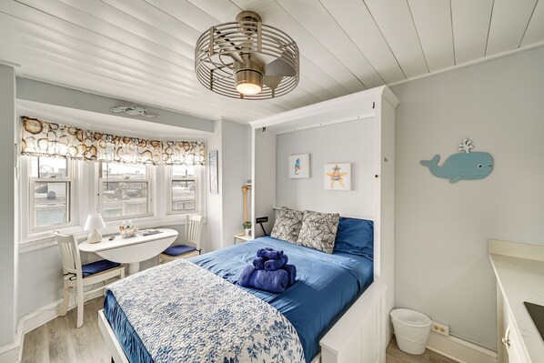 Una habitación con cama, escritorio y ventana con vista al agua.