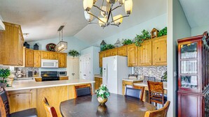 Una cocina con armarios de madera, una isla central con un florero y una mesa de comedor con sillas.