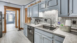 Una cocina con gabinetes grises, lavavajillas, fregadero y cafetera.