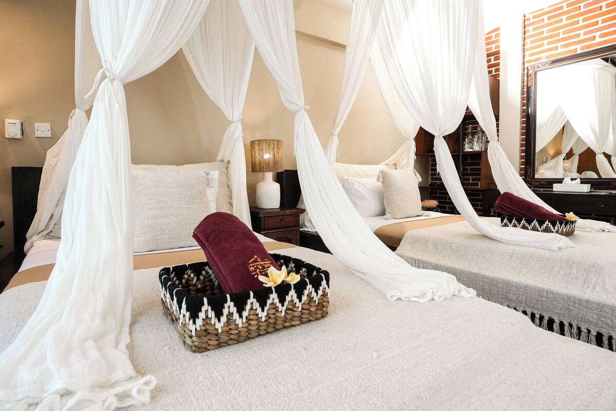 A bedroom with a canopy bed, a bedside table with a lamp, and a mirror.