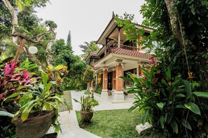 Ein traditionelles Haus mit Ziegeldach, umgeben von üppiger Bepflanzung und einem gepflegten Garten.