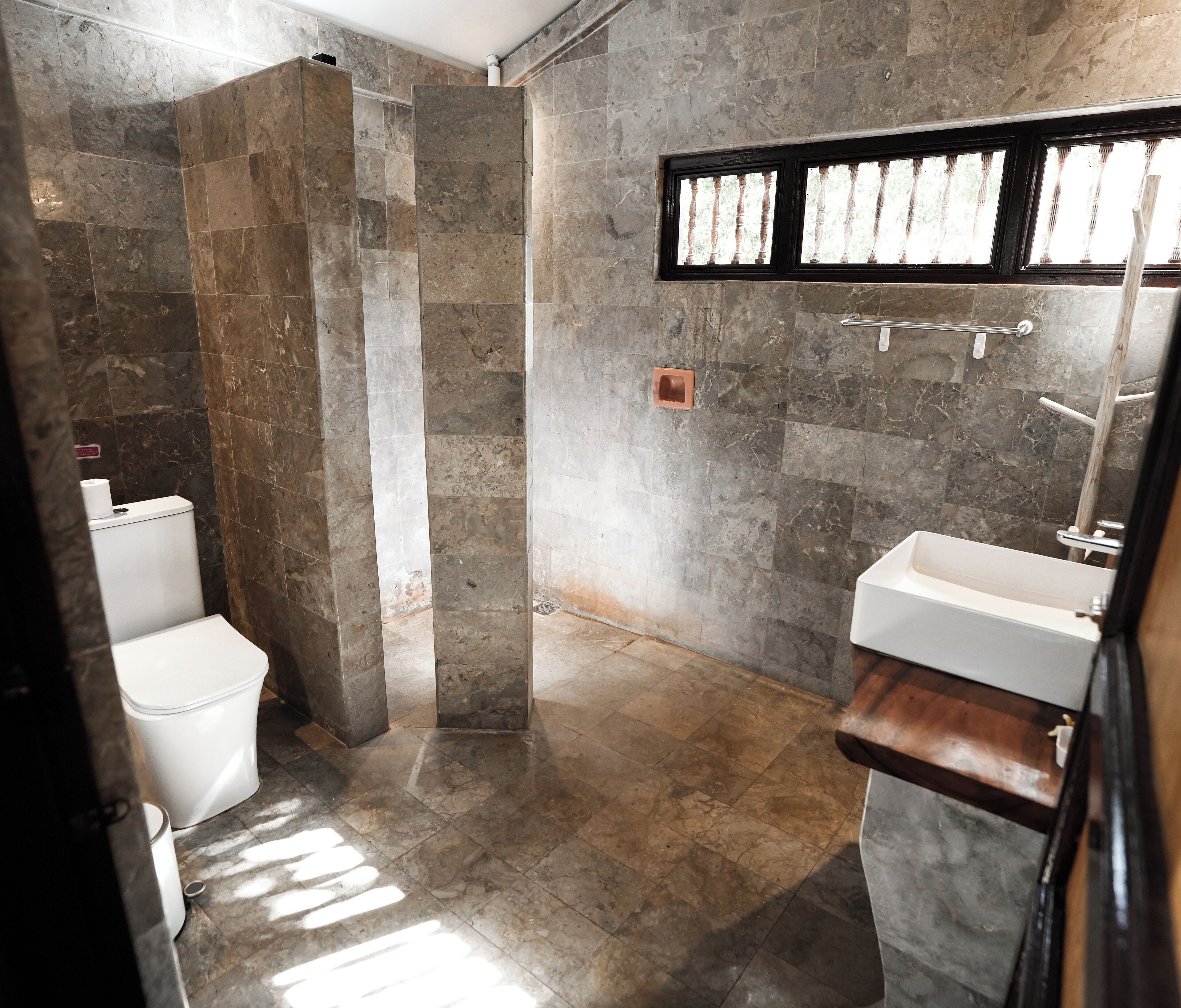A bathroom with a stone shower, a toilet, and a sink.