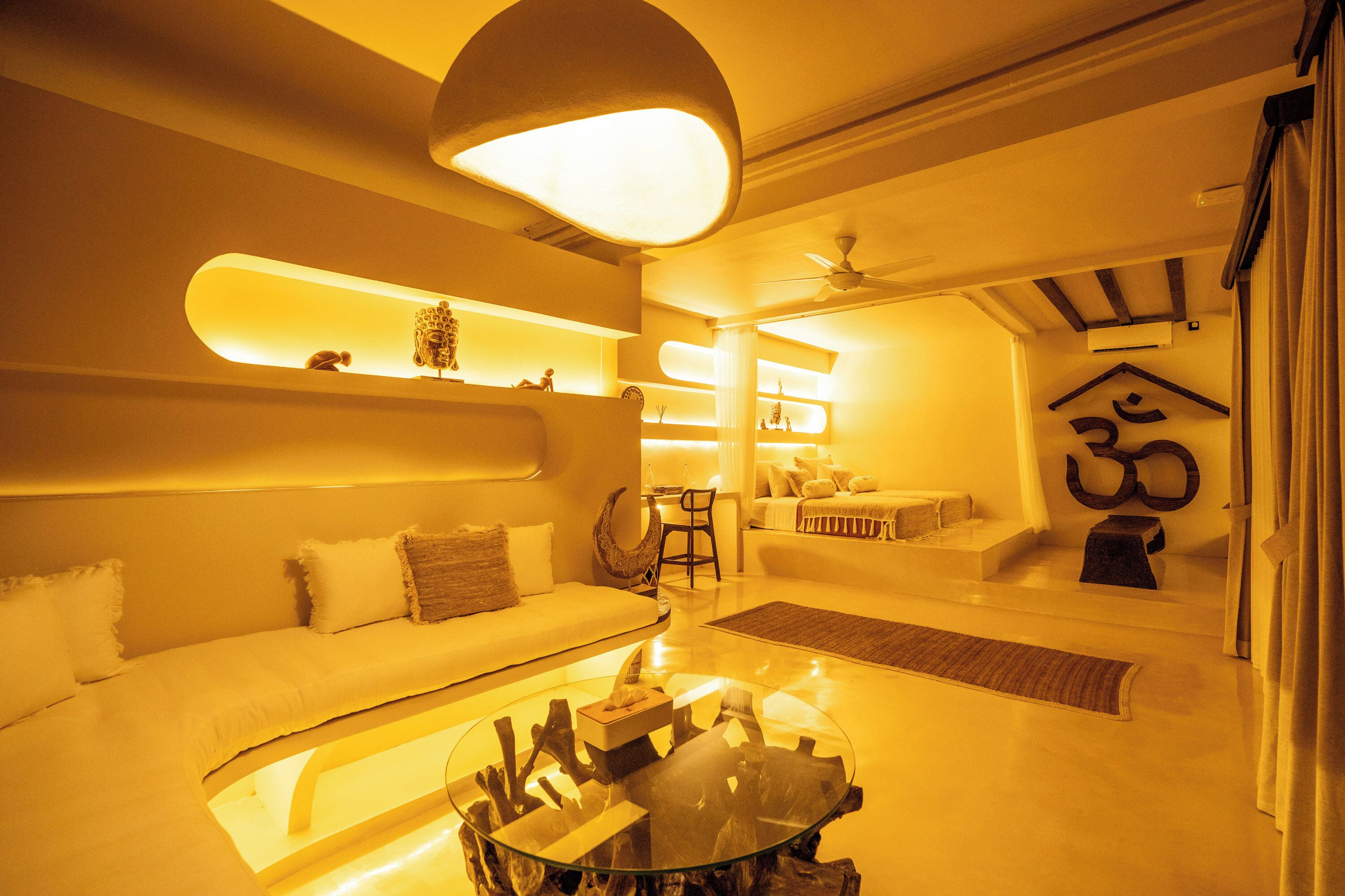A modern living room with a glass coffee table, white sofa, and a ceiling fan.