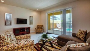 A living room with a sofa set, a coffee table, and a TV on the wall. - Serenity 3 Bedroom Vacation Home 1523 (Clermont)