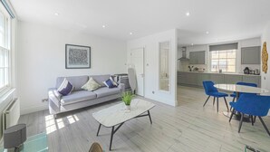 Una sala de estar moderna con un sofá gris, una mesa de centro blanca y sillas azules.