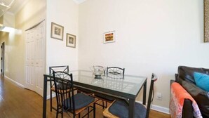 Un coin repas avec une table en verre, quatre chaises et une porte blanche en arrière-plan.