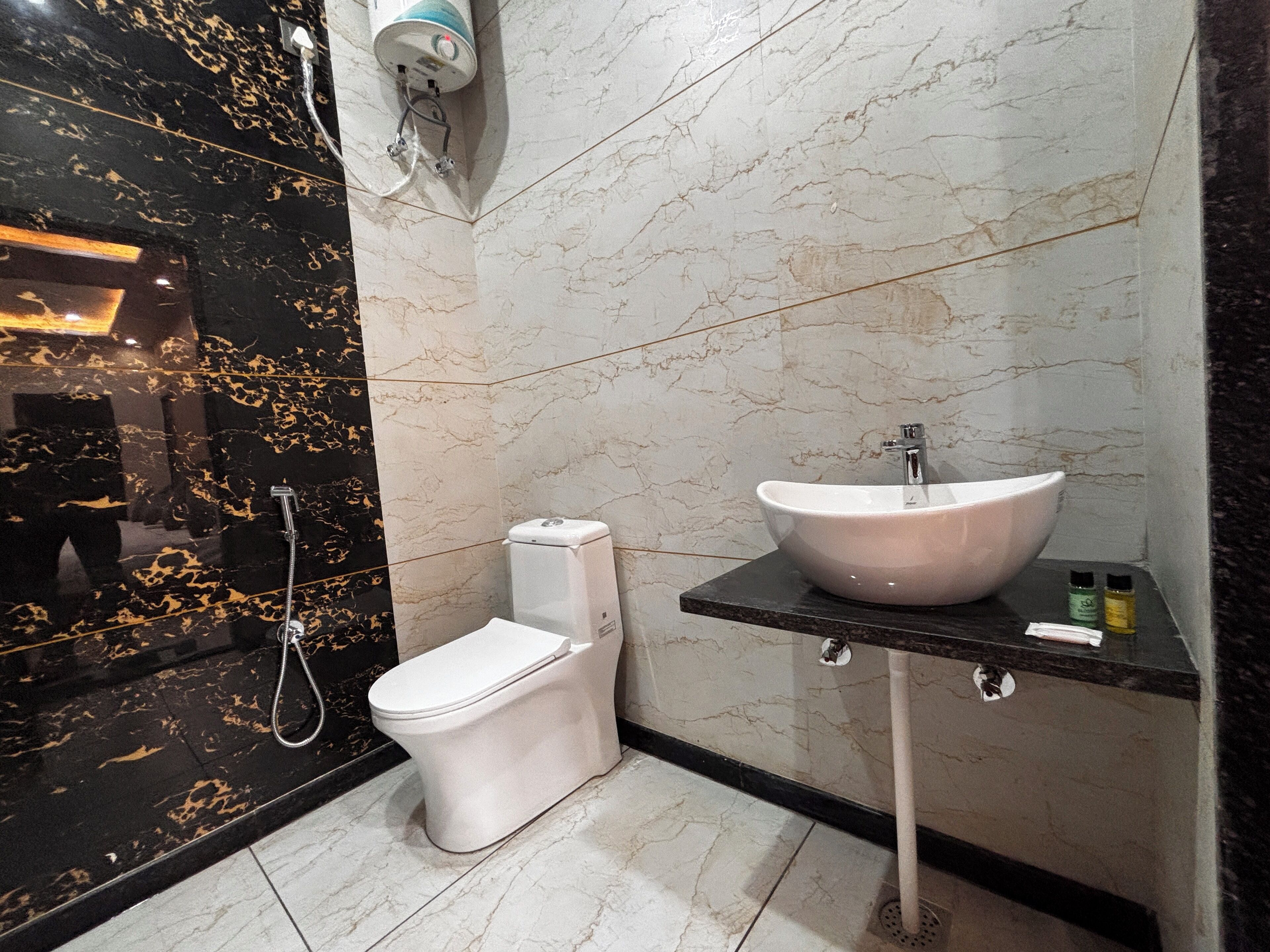 A modern bathroom with a white toilet, a white sink with a marble countertop, and a shower area with black and white marble tiles.