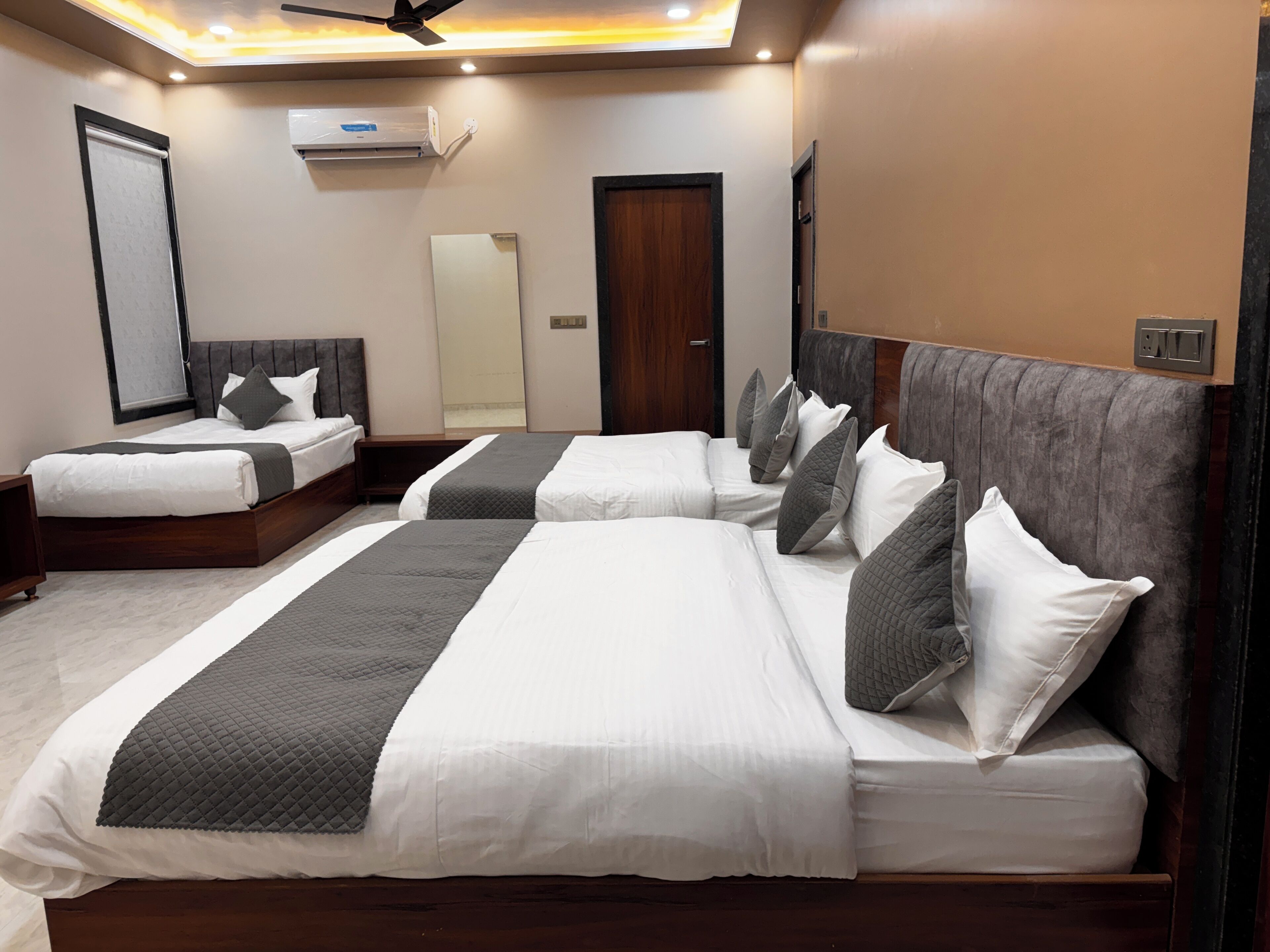 Une chambre d’hôtel avec deux lits, un ventilateur de plafond, un appareil de climatisation et un grand miroir.