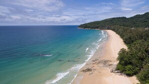 A beach with clear turquoise waters, a sandy shore, and a forested hill in the background. - Villa Rodnaya by Elite Havens (A. Thalang)