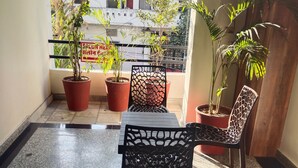 Ein Balkon mit Blumentöpfen, einem Tisch und zwei Stühlen.
