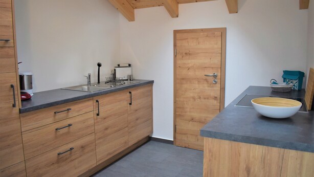 A kitchen with wooden cabinets, a sink, and a countertop. - Wanderlust apartment with 2 bedrooms, kitchen, shower/WC and loggia (Rosenheim)