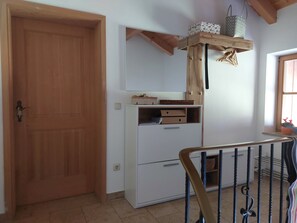 Ein Zimmer mit Holztür, einem weißen Schrank mit Schubladen, einem Regal mit Körben und einem Fenster mit Blick.