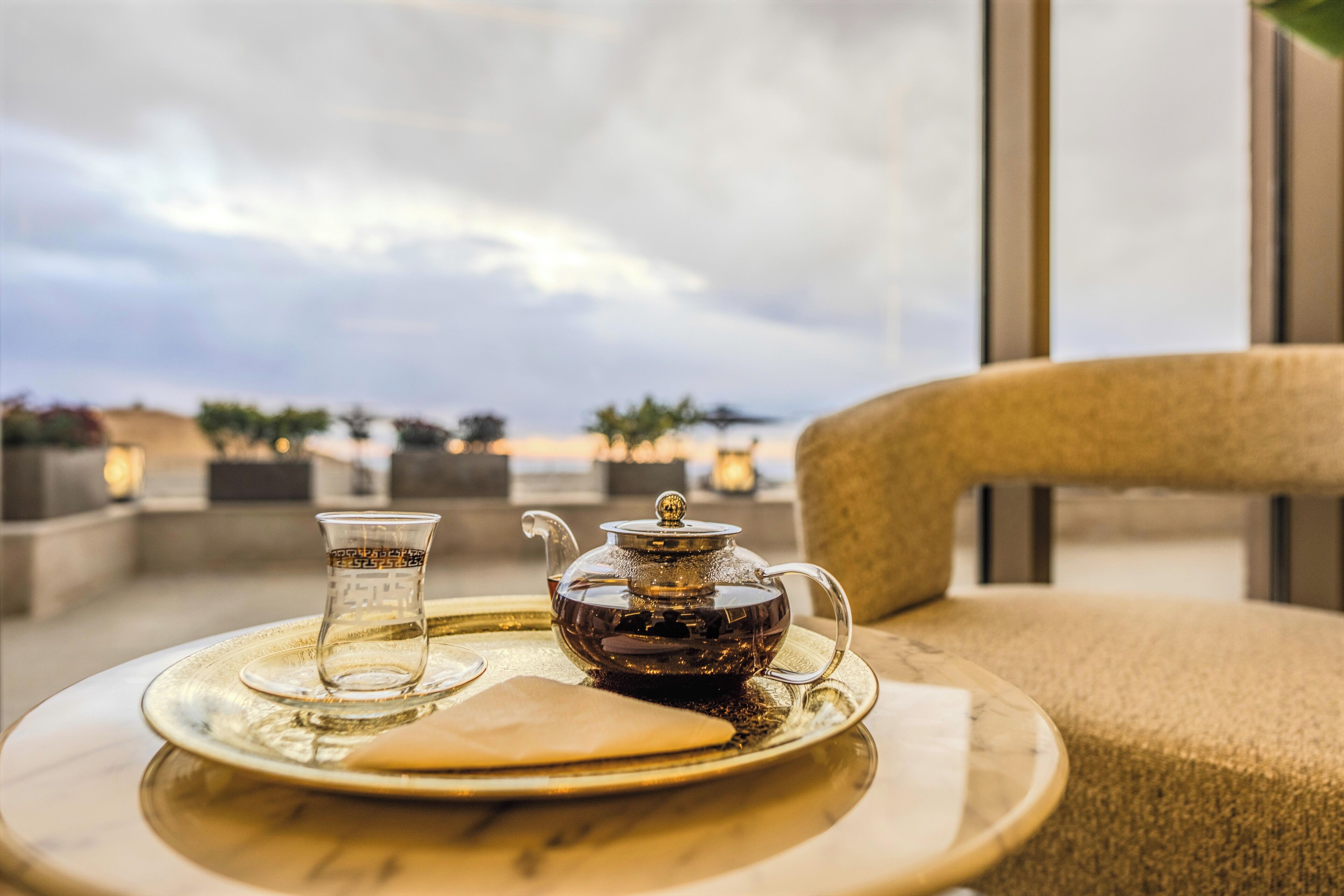 A table with a teapot and two cups on a tray, overlooking a scenic view.