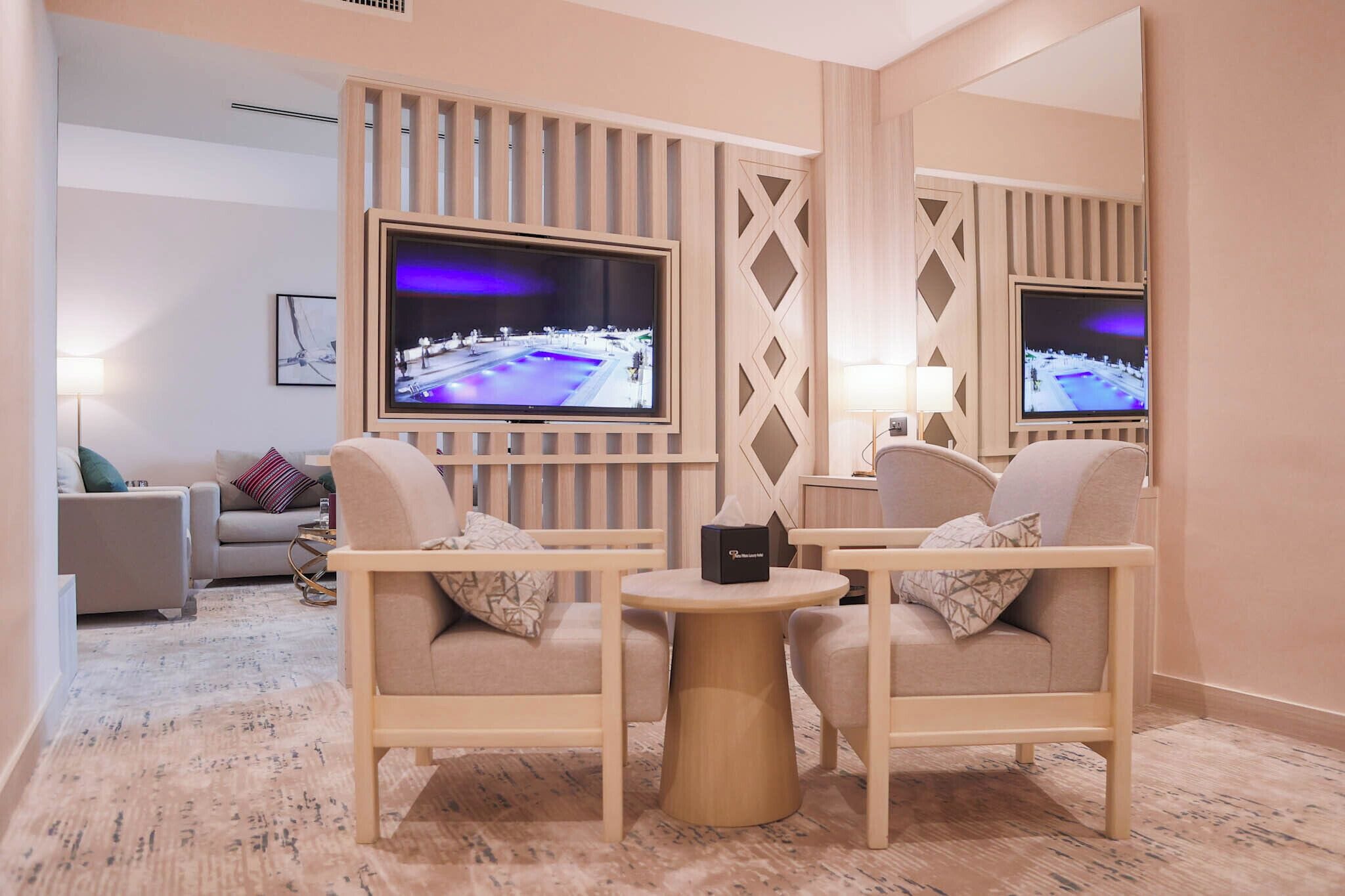 A modern living room with two sofas facing a flat-screen TV, a small round table, and a decorative wall panel.