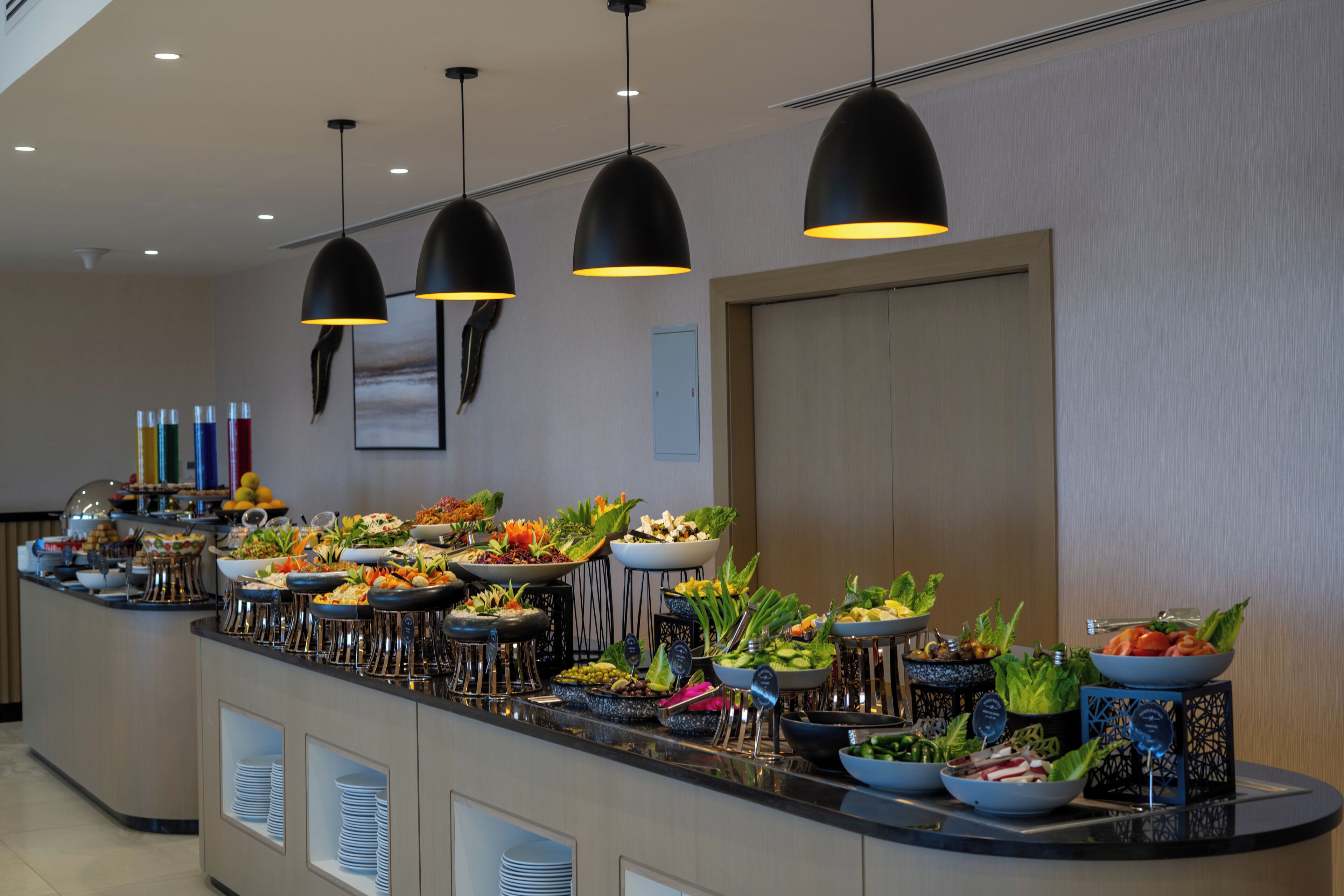 A buffet with various food items and drinks, arranged on a counter with stools.
