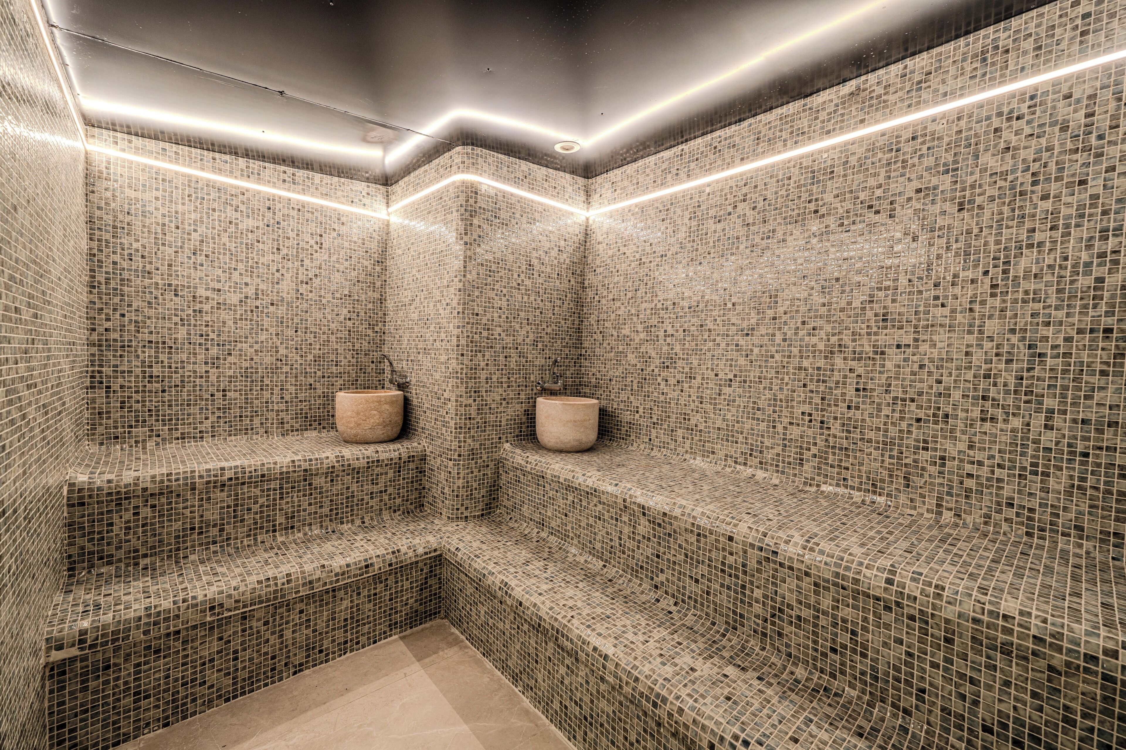 Uma sauna revestida de azulejos com dois bancos e um pilar central.