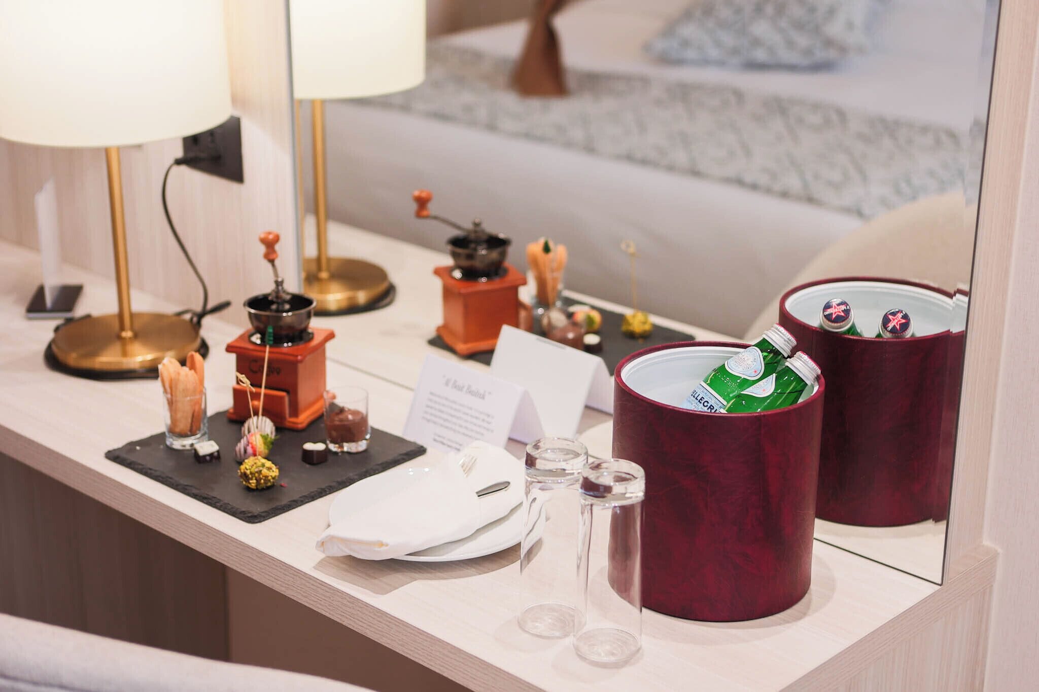 A hotel reception area with a counter displaying various amenities including a coffee machine, a tea set, and a small selection of snacks.