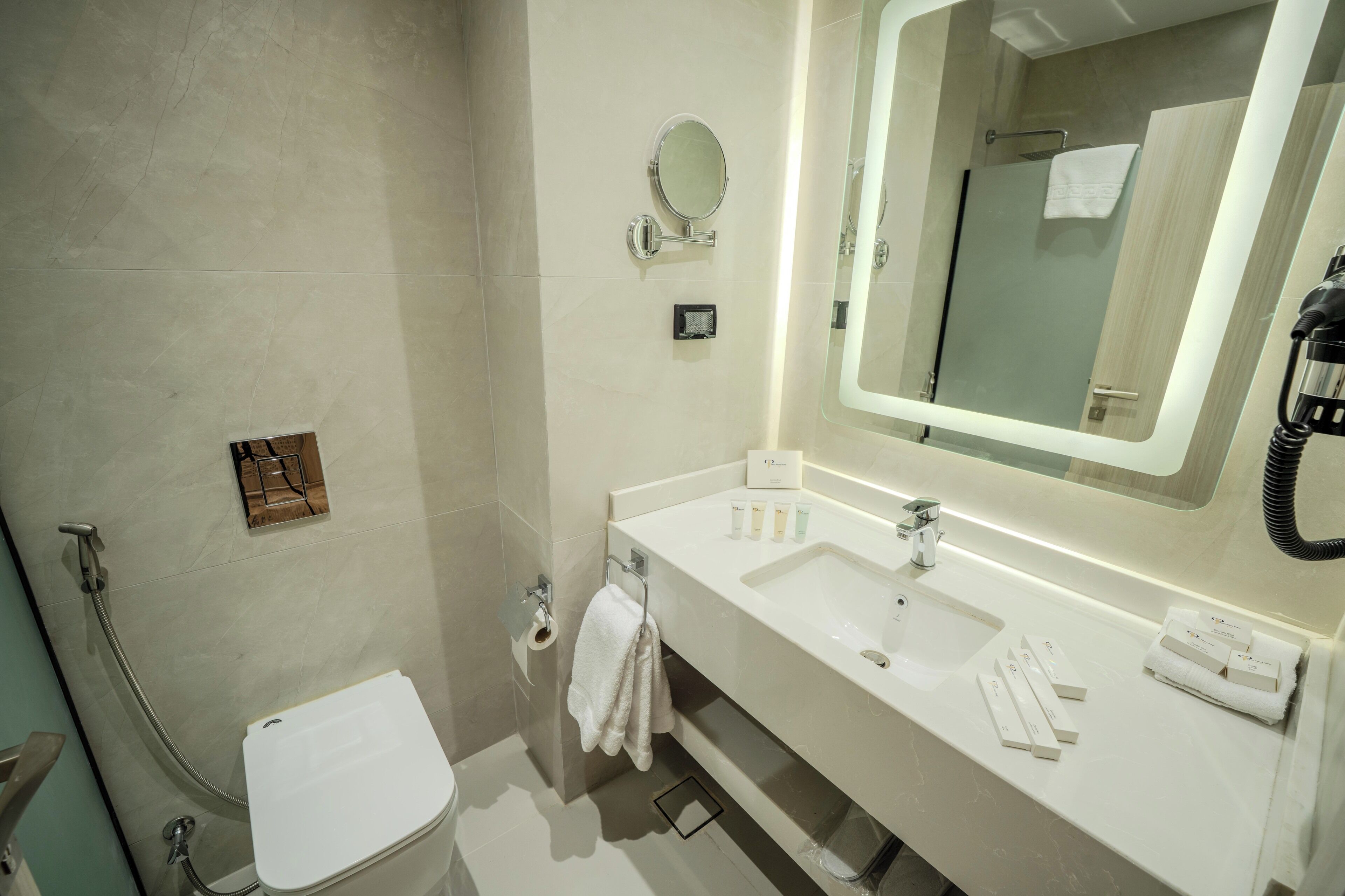 A modern bathroom with a white sink, mirror, and toilet.