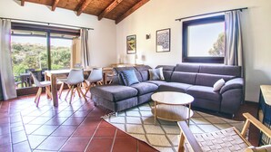 A modern living room with a sectional sofa, a round coffee table, and a dining area with chairs and a table. - Villa Blu with pool in Stintino – Sardinia (Punta de Su Turrione)