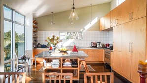 A modern kitchen with a large island, wooden cabinets, and a view of the outdoors. - Roseneath Escape - Panoramic Harbour Views (Wellington)