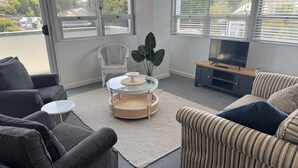 A modern living room with a sofa, armchair, and a glass coffee table. - Chic 2 Bedroom Apartment in Art Deco Napier (Napier)