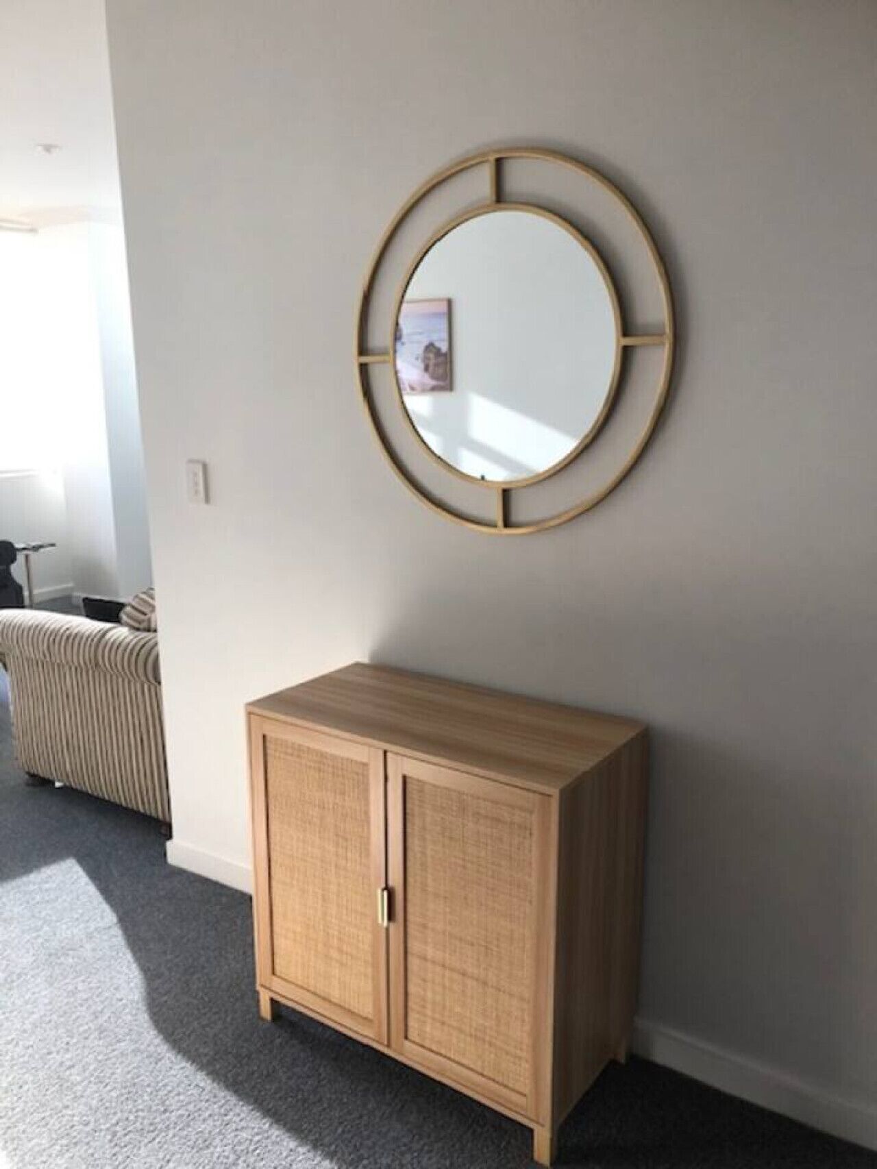 A room with a wooden cabinet and a round mirror on the wall.