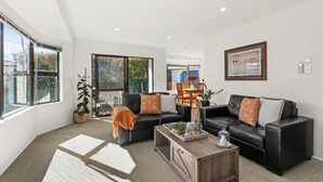 A modern living room with two black sofas, a wooden coffee table, and a large window with a view of the outdoors. - Havelock North Heartbeat (Havelock North)